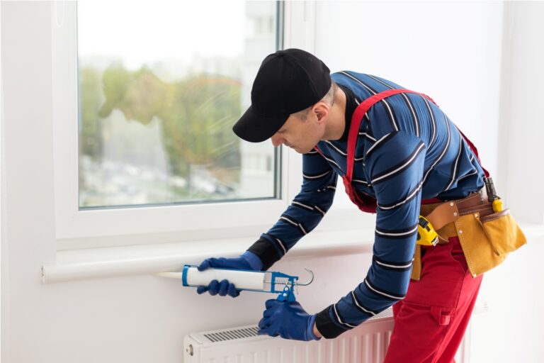 construction worker sealing window with caulk, closeup