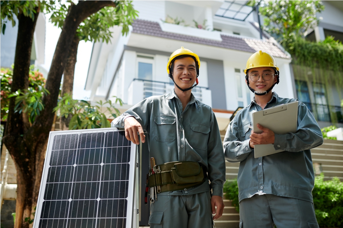 portrait of happy workers standing next to solar panels ready for installation