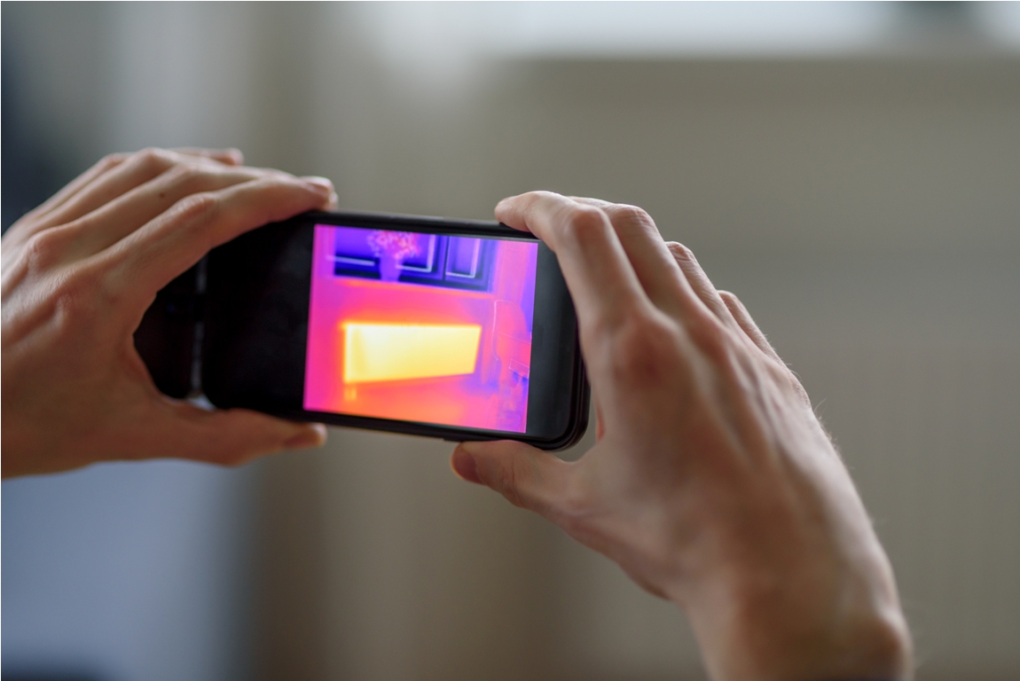 person doing thermal scanning of apartment