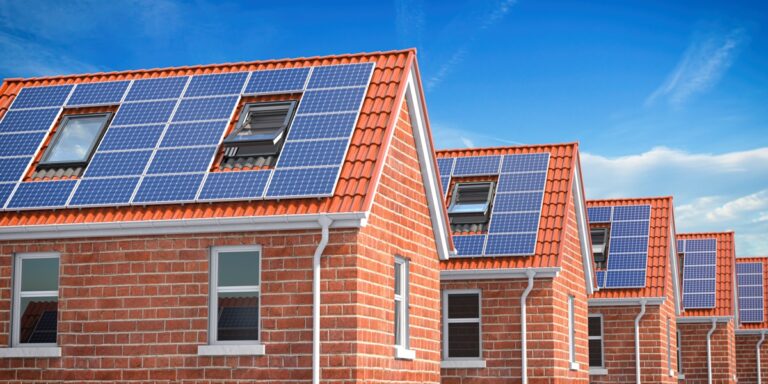 row of house with solar panels on roof on blue sky background.