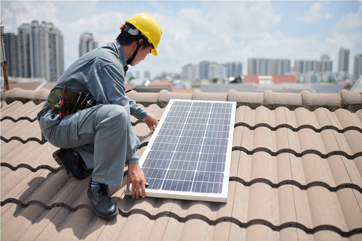 cropped image of worker installing solar panels on roof of residential building