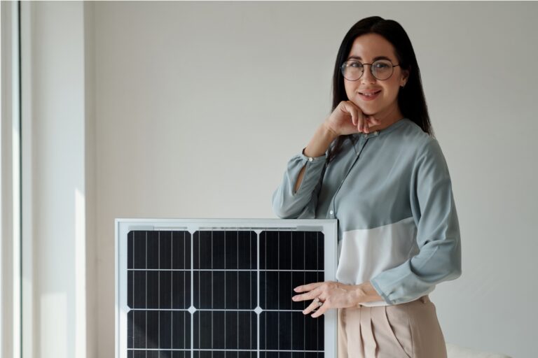 portrait of smiling woman standing next to solar panel she bhought for home